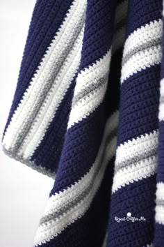 a blue and white striped crocheted blanket hanging from a hook on a wall