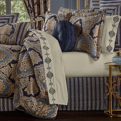 a bed covered in blue and gold comforter next to a window