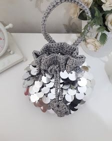 a crocheted purse sitting on top of a table next to a vase with flowers