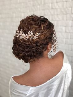 a woman wearing a bridal hair comb with leaves on it's head, in front of a brick wall