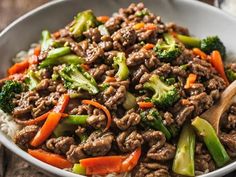 a close up of a bowl of food with broccoli and carrots in it