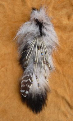 an animal's head with feathers and beads on it sitting on a brown surface