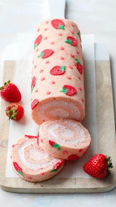 sliced strawberry roll on cutting board with strawberries