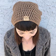 a woman wearing a brown crochet hat with a tag on it's side