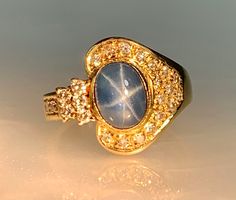 Star Sapphire Ring, Star Sapphire Ring for Women, Galaxy Ring, Celestial Ring, Vintage Star Sapphire Ring, Blue Star Sapphire, OOAK Ring, Lunar Ring An enchanting vintage blue star sapphire ring featuring a lustrous oval shaped center stone weighing 2.40 carats accented by 0.48 carats of sparkling white diamonds set in solid 18k yellow gold.  *Ring size: US 6 1/4 *Ring weight: 5.50 Grams *Center stone dimensions: 8X6mm Gold Sapphire Ring Star, Blue Star Sapphire Ring, Star Sapphire Ring, Galaxy Ring, Celestial Ring, Blue Star Sapphire, Vintage Star, Star Sapphire, Ring Blue