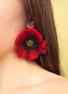 a close up of a person wearing earrings with a flower on the back of their ear