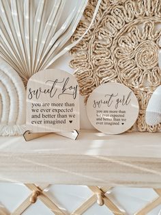 two wooden plaques sitting on top of a white shelf next to a decorative wall hanging