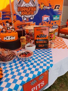 there is a table with food on it at a race car themed birthday party in the grass