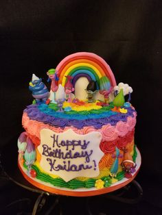 a birthday cake with rainbow frosting and decorations