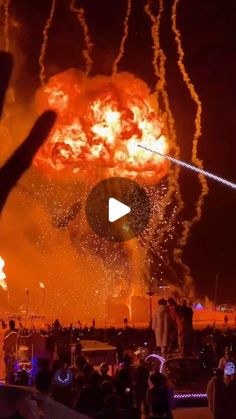 people watching fireworks in the night sky with their hands up and one person taking a photo