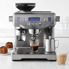 an espresso machine sitting on top of a counter next to a plate of croissants