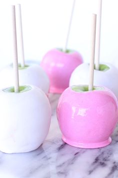 four white and pink apples with toothpicks in them on a marble countertop