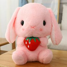 a pink stuffed animal with a strawberry on it's chest sitting on a table