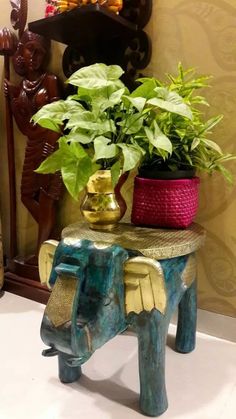 an elephant shaped table with a potted plant on it's top and other decorative items in the background