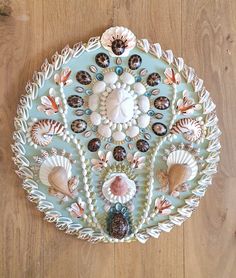 a decorative plate with shells and seashells on the bottom, sitting on a wooden floor