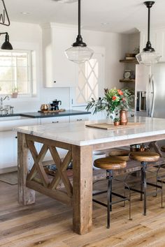 a white table and bench in a room with wood flooring, glass cabinets and windows