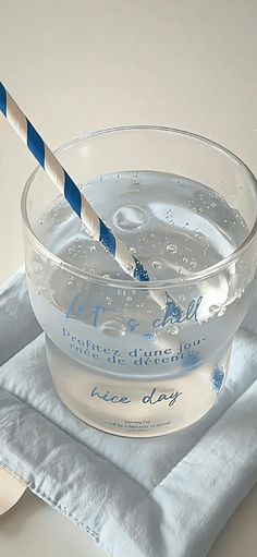 a glass bowl filled with ice water and a blue striped drinking straw in it on top of a napkin