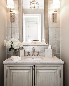 a bathroom vanity with marble counter top and white flowers in vase on the sink area