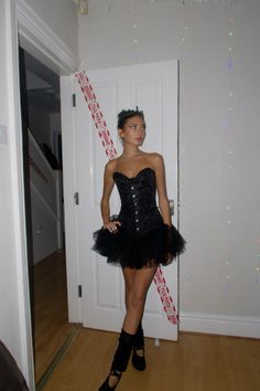 a woman in a short black dress is standing by a door and posing for the camera