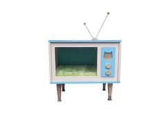 an old fashioned television set with grass in the front and on it's stand