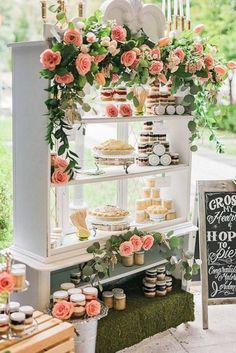 a display case filled with cakes and cupcakes on top of a lush green field