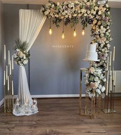 a wedding arch with flowers and candles on the side is decorated in gold, white and pink