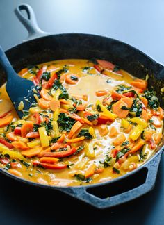 a pan filled with vegetables and cheese on top of a table next to a spoon