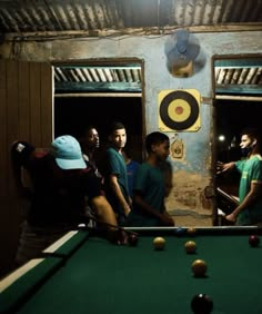 a group of men standing around a pool table