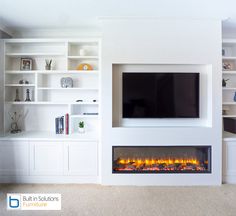 a white living room with a fireplace and built - in bookshelves on either side