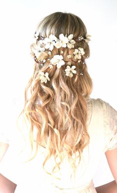 a woman with long curly hair and flowers in her hair is shown from the back