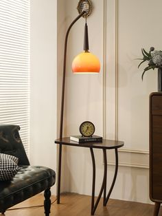 a lamp that is sitting on top of a table next to a chair and clock