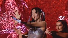 two women are dancing in front of a red background