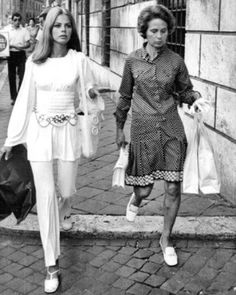 two women walking down the street carrying shopping bags