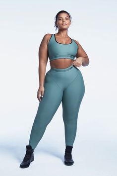 a woman in a green sports bra top and leggings poses for the camera