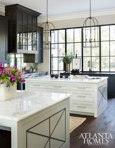 a kitchen with black cabinets and white marble counter tops is shown in front of a large window