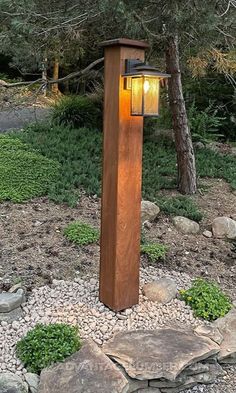 a wooden post with a light on it in the middle of some rocks and trees