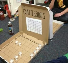 a man sitting on the floor next to a cardboard box with a game in it