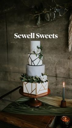 a three - tiered cake with greenery and candles sits on a wooden table