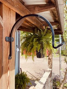 a wooden porch with a potted plant on the side and an outdoor shower attached to it