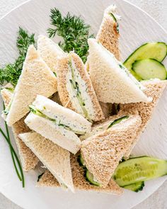 a white plate topped with cucumbers and sandwiches