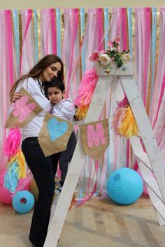 a woman and child are posing for a photo in front of a backdrop with balloons