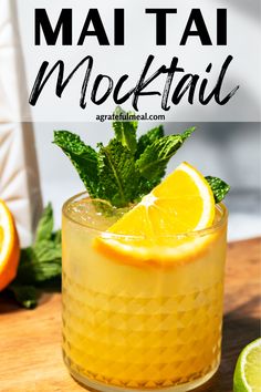 a cocktail with oranges and mint garnish on the rim, sitting on a wooden table