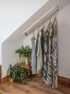 some clothes hanging on a rail next to a potted plant