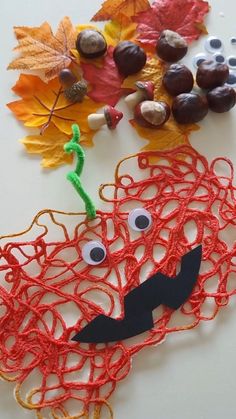 an arts and crafts project for kids to make with leaves, acorns and yarn