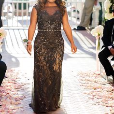 a woman in a black dress walking down the aisle