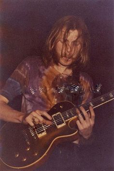 a man with long hair playing an electric guitar