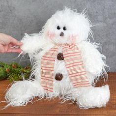 a white teddy bear with a red and white striped scarf