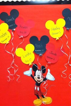 a mickey mouse bulletin board with name tags attached to it and balloons in the air