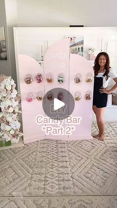 a woman standing in front of a candy bar sign with flowers and vases behind it