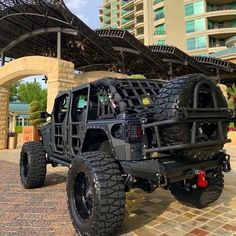 a large black truck parked in front of a tall building next to a stone walkway